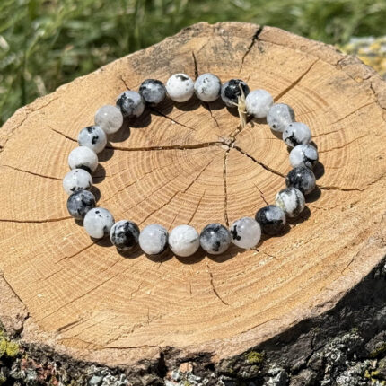 Moonstone crystal bracelet placed on a wooden block with a blurred garden background.